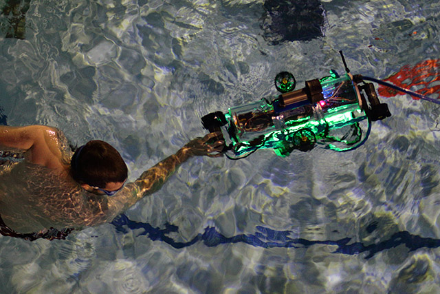 [Picture] An aerial view of Peter and the AUV in the water. It was dark outside and the orange marker was barely detectable.