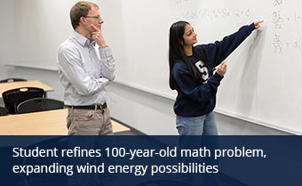Two individuals examine a math problem on a whiteboard