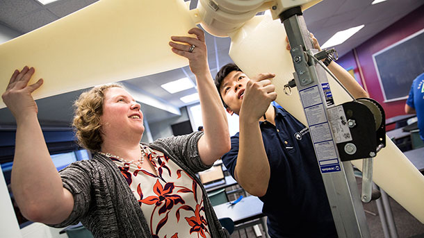 Susan Stewart and Chee Hau Teoh, a junior in mechanical and nuclear engineering attach blades to the tower of a small-scale wind turbine prototype built for demonstration purposes.