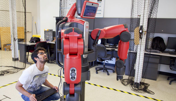 A graduate student conducts an experiment with a Baxter robot in the Robot Ethics and Aerial Vehicles Lab.